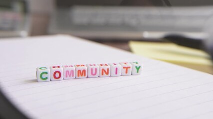 A magnifying glass passes over an image of some blocks that have the word "community" written on them. - Powered by Adobe