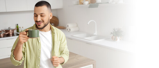 Young man with ceramic cup in kitchen