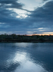 Moody Vertical Landscape of Dark Water Reflecting a Cloudy Dusk Sky
