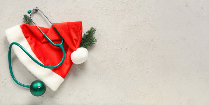 Stethoscope with Christmas tree branches and Santa hat on light background