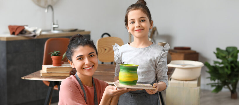 Little girl and her mother with clay pot at home