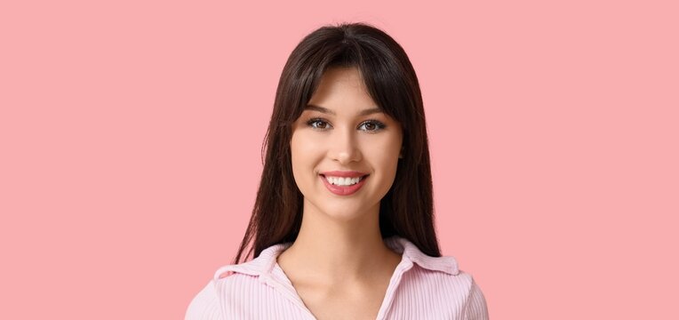 Smiling young woman on pink background