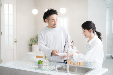 キッチンで皿洗いをする夫婦　共働きなどのイメージ