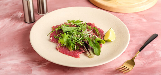 Plate with tasty veal carpaccio on color background