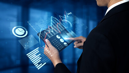 A business professional engages with a tablet displaying financial analytics and market trends while surrounded by a modern office environment, showcasing technology in action. Scalp