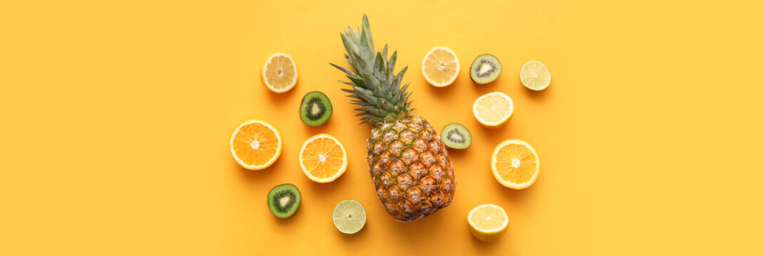 Fresh pineapple with different citrus fruits and kiwi on orange background