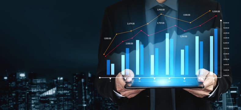 A business professional holds a tablet displaying digital financial data with graphs and charts, set against a cityscape. Ideal for technology and finance concepts. Scalp