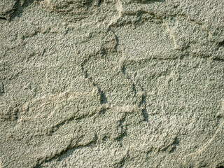 Detailed texture of rough green stone wall under sunlight, abstract natural background for construction, design or 3D modeling references.
