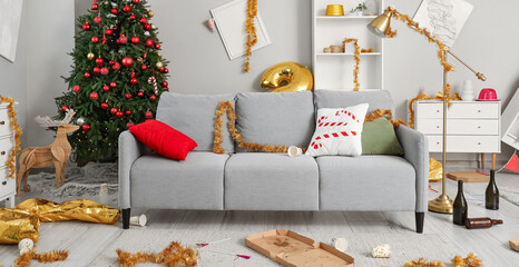 Interior of messy living room with sofa and tinsel after New Year party