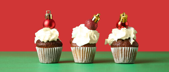 Sweet cupcakes with Christmas balls on color background
