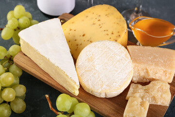 Wooden board with different types of cheese on table