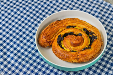 Close up view of one raisin roll on white plate. napkin background. copy space, empty, free, negative, text, design.
