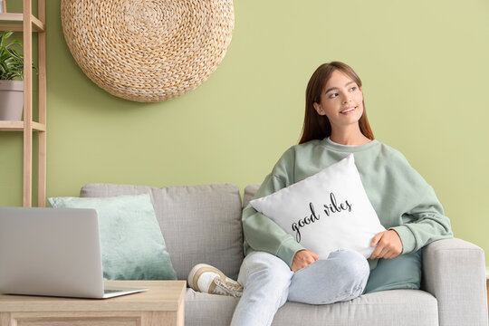 Pretty young woman sitting on sofa  at home - Powered by Adobe