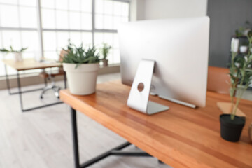 Blurred view of workplace with computer and plants in office