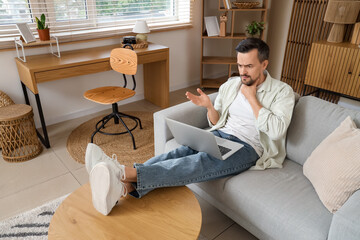 Handsome man with thyroid gland problem and laptop video chatting on sofa at home