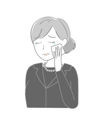 涙を拭く喪服のシニア女性