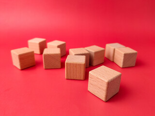The image displays several unfinished, natural wooden cubes on a red surface