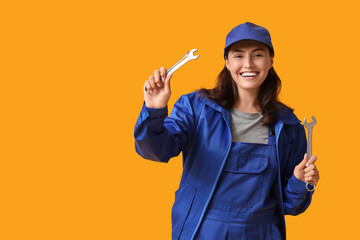 Young female mechanic with wrenches on yellow background. Woman in male profession concept