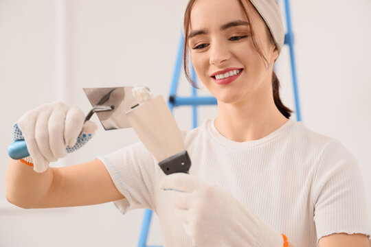 Young woman with putty knives in room, closeup