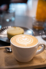 Close-up of a horizontal photo of a barista cafe focusing on a pistachio alfajor with white chocolate and orange juice in the background cenital