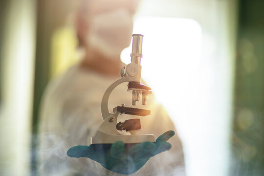 Scientist presenting a laboratory microscope in bright medical research environment with protective gloves
