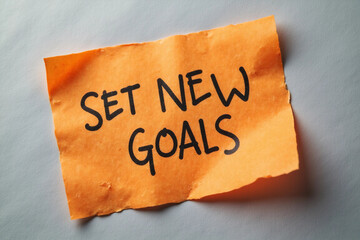 Set New Goals symbol. Concept words Set New Goals on orange steaky note. Beautiful grey background. Business and Set New Goals concept. Copy space. 3d rendering.