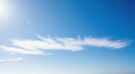 A serene blue sky with wispy white clouds and a bright sun shining down.