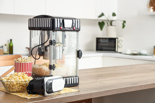 Modern popcorn machine and VR glasses on table in kitchen