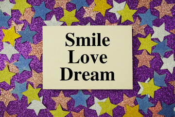 "Smile Love Dream" quotes on paper card with purple background with colorful glitter stars