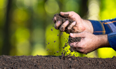 Farmers hand holding fertile soil close-up. Farmer checking soil quality on farm. Farmer pouring...
