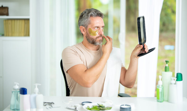 Male beauty facial treatment for healthy skin. Handsome man using facial cosmetic products to enhance facial beauty. Man practicing facial care for a beauty routine. Aged male skin concept.