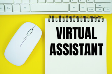 Notepad with the text "Virtual Assistant" with white keyboard and wireless mouse on yellow background