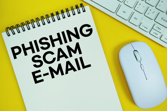 Notepad with the text "E-Mail Phishing Scams" with white keyboard and wireless mouse on yellow background