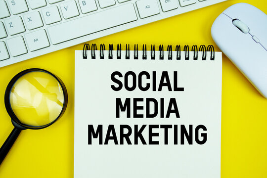 Notepad with the text "SMM Social Media Marketing" and white keyboard, wireless mouse, magnifying glass on yellow background