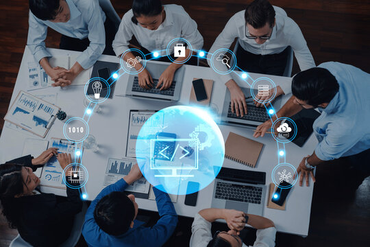 A diverse team of professionals engages in a collaborative meeting on technology projects, utilizing laptops and visual data, emphasizing innovation and strategy development. Trope - Powered by Adobe