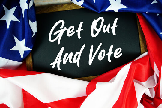 American flag with blackboard  "Get Out And Vote" on wooden background
