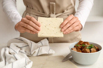 Woman with tasty tofu cheese in kitchen