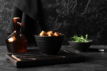 Bowl with pieces of fried tofu cheese on black background