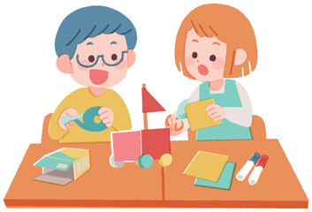 机に座って一緒に工作する小学生の男の子と女の子