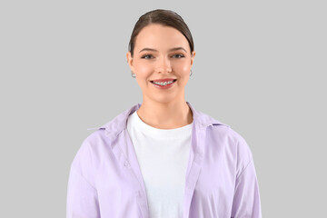 Young woman with dental braces smiling on light background