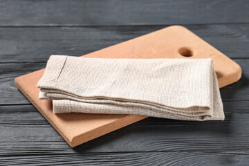 Cutting board with napkin on black wooden table, closeup