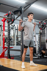 Fototapeta premium Asian man client in sportswear standing and exercising with barbell weight lifting equipment in gym.