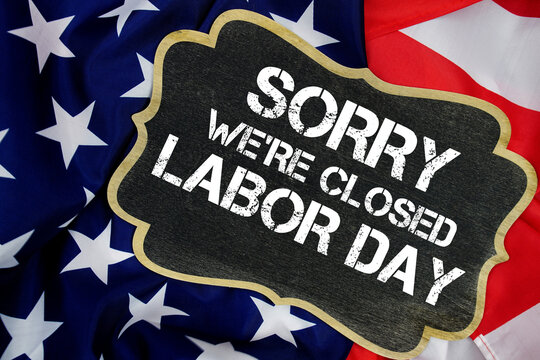 Sorry We're Closed Labor Day written on blackboard with USA flag background
