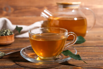 Glass cup of hot green tea on wooden background