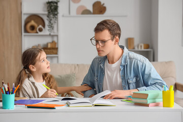 Teenage girl studying with tutor at table in room
