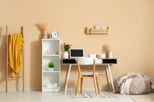 Stylish workspace with modern laptop and beautiful flowers in home office