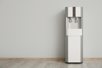 Modern water cooler near white wall in room