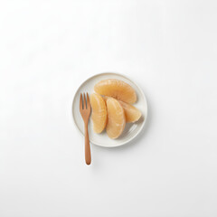 Pomelo Fruit Overhead shot of juicy, pinkish segments on a round white plate with a wooden fork