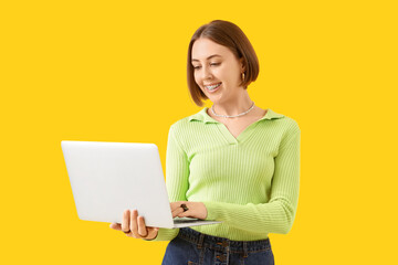 Naklejka premium Young woman with dental braces using laptop on yellow background