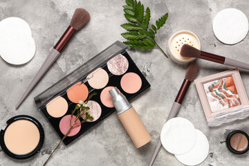 Composition with cotton pads, green twig and makeup products on grey grunge background, closeup